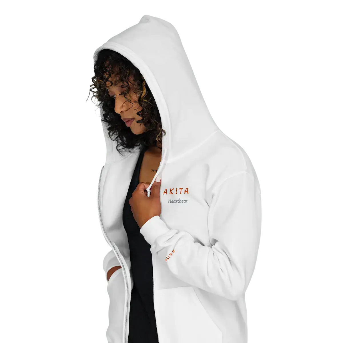 Left‑profile view of a woman wearing a unisex heavy‑blend zip hoodie with the minimal ‘Akita’ and Heartbeat design, featured as the lead image for the Design Shop